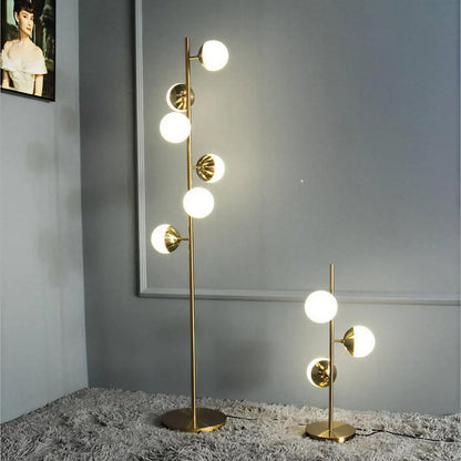 Lampada da terra oro con paralumi a globo in vetro e base in marmo